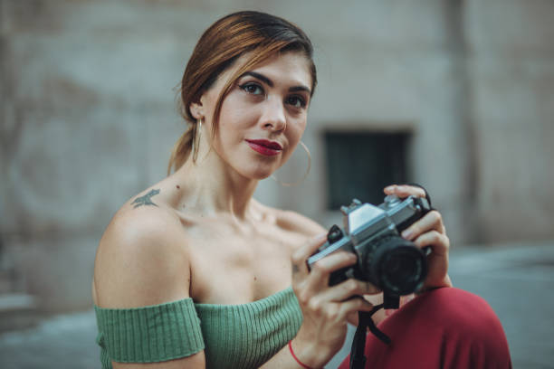 Young woman in fashionable dress poses against brick wall.
