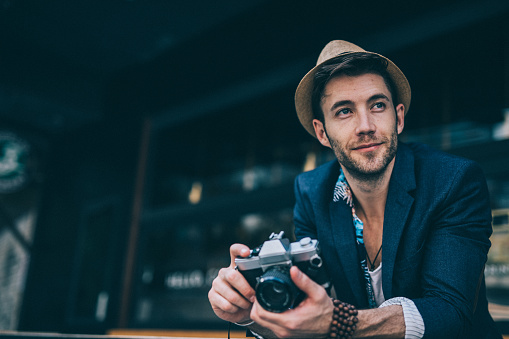 Man photographer holding digital camera and taking photos outdoors