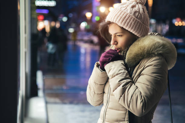 Woman is feeling cold downtown Young brunette woman standing in front of store window and freezing shivering stock pictures, royalty-free photos & images