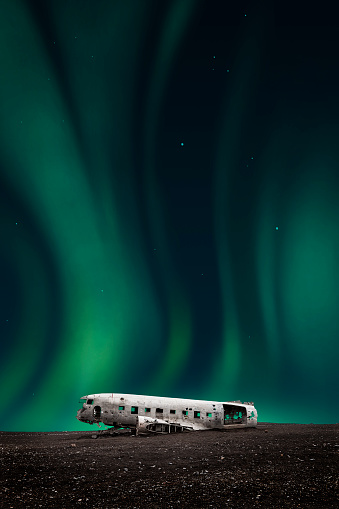 green northern lights over the white wreck of the DC-3 plane on the black beach of Vik. icelandic aurora borealis
