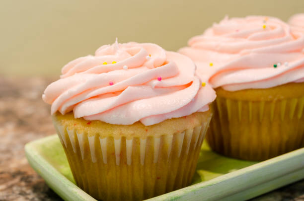 istock Frosted cupcakes. Light pink icing swirled on cherry chip cupcakes, sprinkled with colorful sprinkles. 1034008092
