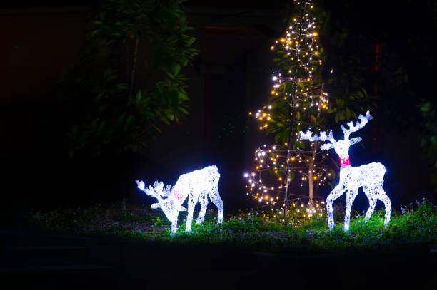 Illuminated Christmas reindeer street lights decorations with a Christmas tree in someoneâs front yard.