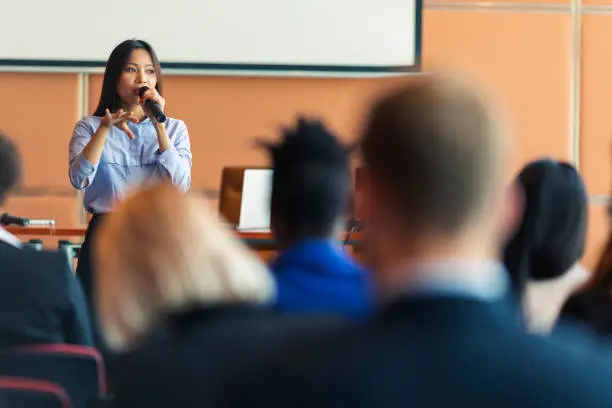 An Asian female presenter interacting with the audience at a business presentation in the board room