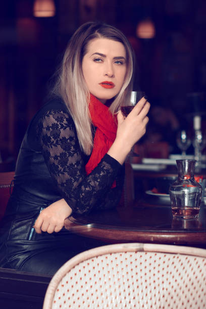 lifestyle shot of blond hair woman drinking glass of wine inside restaurant.