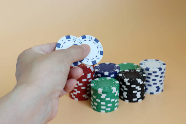 istock Hands holding two casino chips with a pile of casino chips. 1034049986