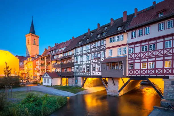 Classic panoramic view of the historic city center of Erfurt with famous Kraemerbruecke bridge illuminated at beautiful twilight during blue hour, Thueringen, Germany