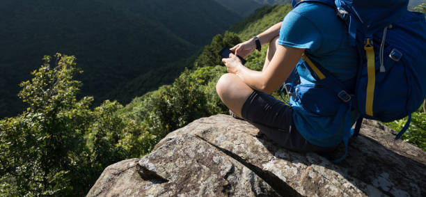 istock Woman hiker using smartphone on mountain cliff edge 1034123242