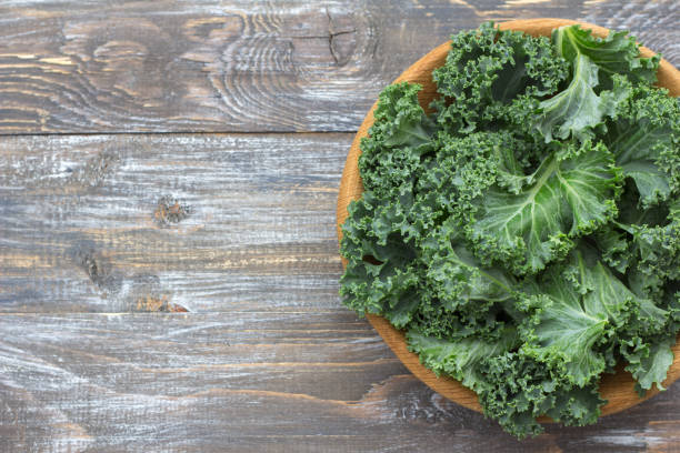 istock Fresh green curly kale leaves on a wooden table 1034131824