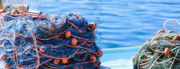 pilhas de redes de pesca no mar azul de fundo de água. porto de marsaxlokk, malta - enfiada de peixes - fotografias e filmes do acervo