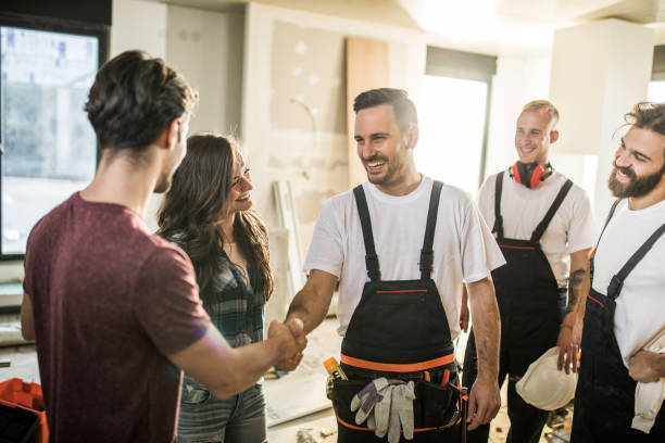 equipe de operários felizes acolher um casal para o apartamento deles. - artesão - fotografias e filmes do acervo