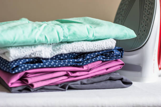 istock Iron on the ironing board and non-ironed clothes 1034162950