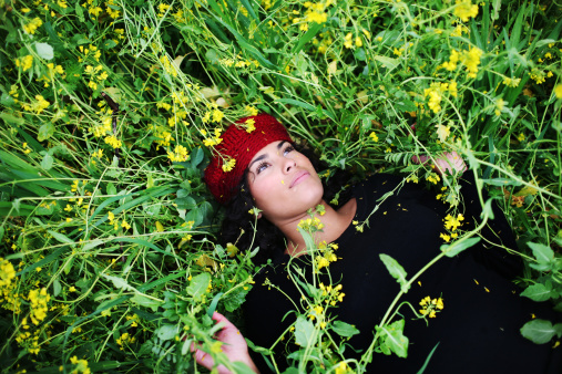 A young latina woman in a vineyard surrounded by mustard flowers.