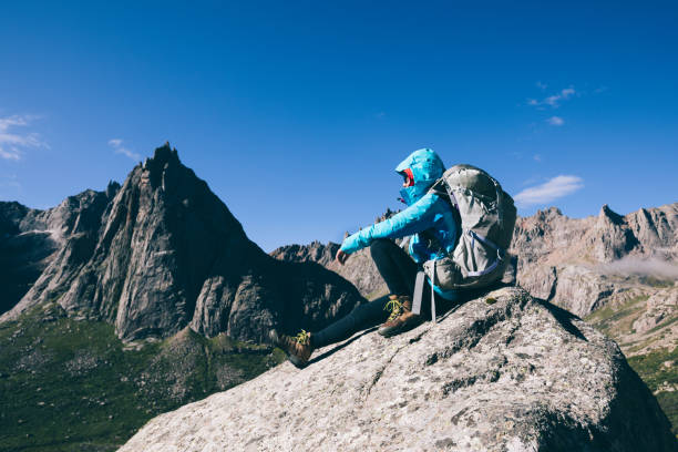 istock Successful woman with backpack hiking in sunrise mountains 1034168396
