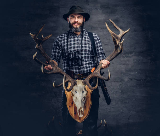 istock Bearded hunter in a fleece shirt and hat holds his trophy. 1034168630