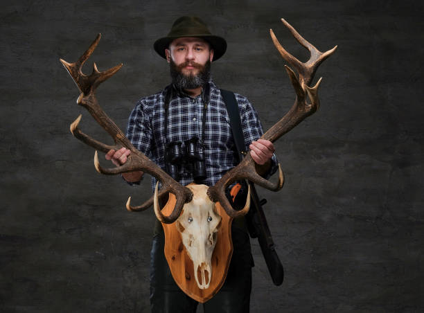 istock Bearded hunter in a fleece shirt and hat holds his trophy. 1034170862