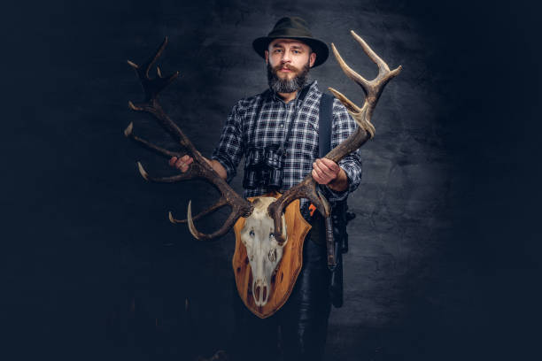 istock Bearded hunter in a fleece shirt and hat holds his trophy. 1034171612