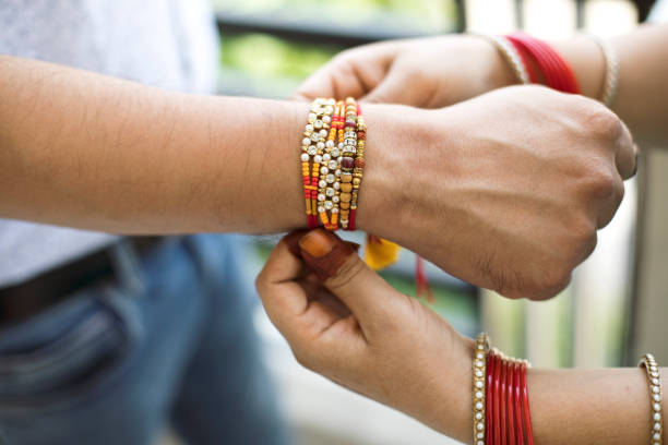 Indian young sister tying rakhi on brother's wrist, a tradition on Raksha Bandhan festival Indian young sister tying rakhi on brother's wrist, a tradition on Raksha Bandhan festival rakhi stock pictures, royalty-free photos & images
