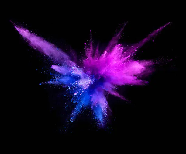 Photo of Explosion of coloured powder isolated on black background.