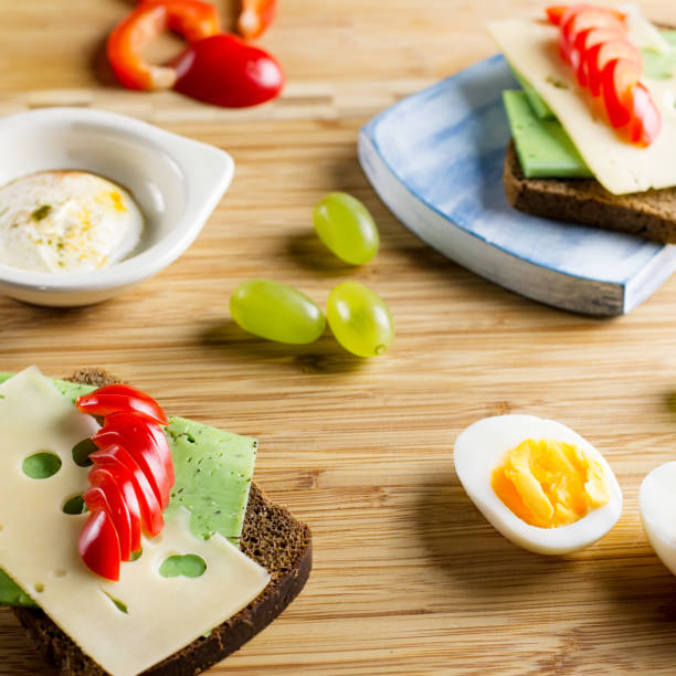 Breakfast table with cheese sandwiches, sausage, vegetables, hard boiled eggs and fruits