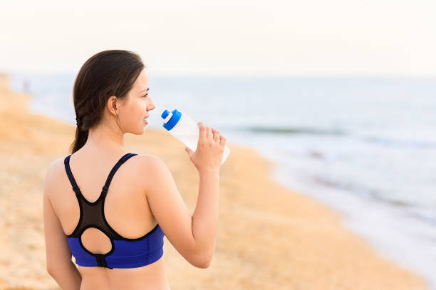 istock woman drinks water on the sea beach 1034187788