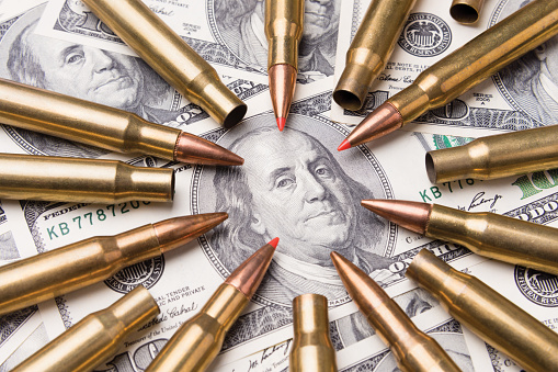 concept of live ammunition is aimed at a portrait of Benjamin Franklin on a hundred dollar bill. The symbol of war and danger