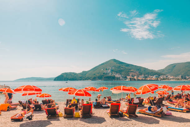 budva, montenegro - 21 luglio 2018: persone sdraiate ai lettini al mare con una splendida vista sul mare e sulle montagne - budva foto e immagini stock