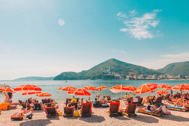 BUDVA, MONTENEGRO - July 21, 2018: people laying at sun loungers at seaside with beautiful view of sea and mountains BUDVA, MONTENEGRO - July 21, 2018: people laying at sun loungers at seaside with beautiful view of sea and mountains. copy space budva stock pictures, royalty-free photos & images
