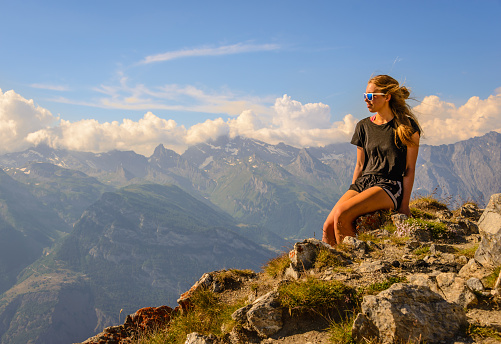 A female hiker sitting on a mountain top at sunset in the Valais region of Switzerland.