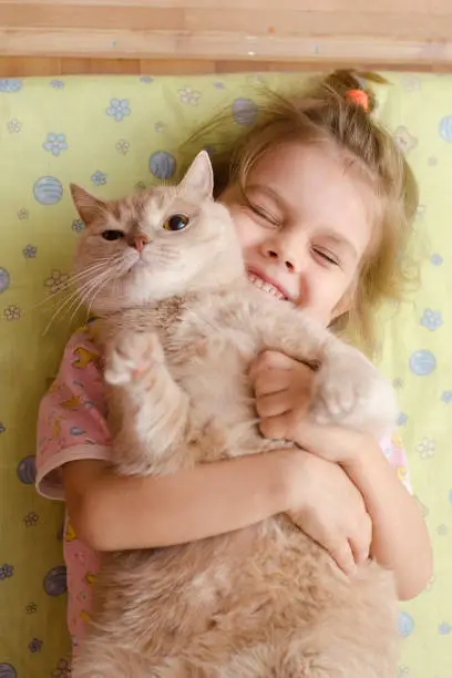 Photo of The girl closed her eyes with joy, hugging her pet cat