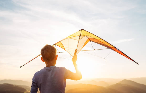 istock Boy prepare start to fly a kite over the sunset mountain hills 1034211612