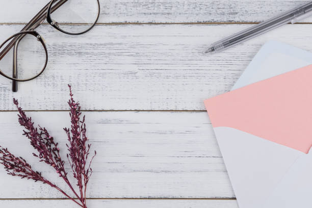 istock Blank pink card in white envelop, eyeglasses and black pen 1034211650