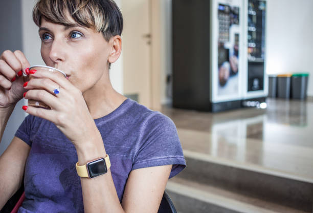 Adult Woman Drinking Coffee from a Vending Machine.