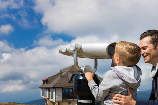 istock Son and father looking through binoculars at mountain view point. 1034217042