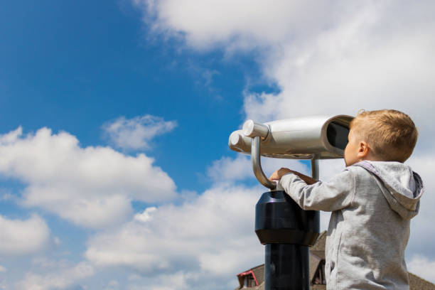 istock Kid looking looking through coin operated binoculars against the sky. 1034217052