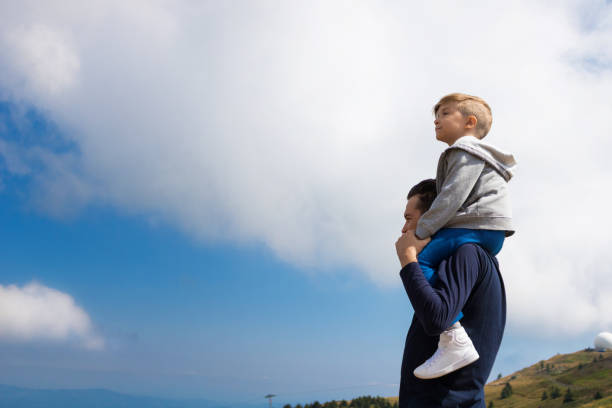 istock Father carrying son on shoulders and looking at view. 1034217658