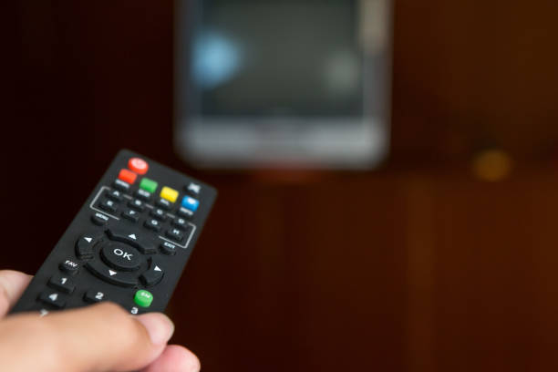 istock Remote TV in hand on background blurred 1034221730
