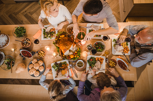 High angle view of extended family communicating while having Thanksgiving dinner at dining table.