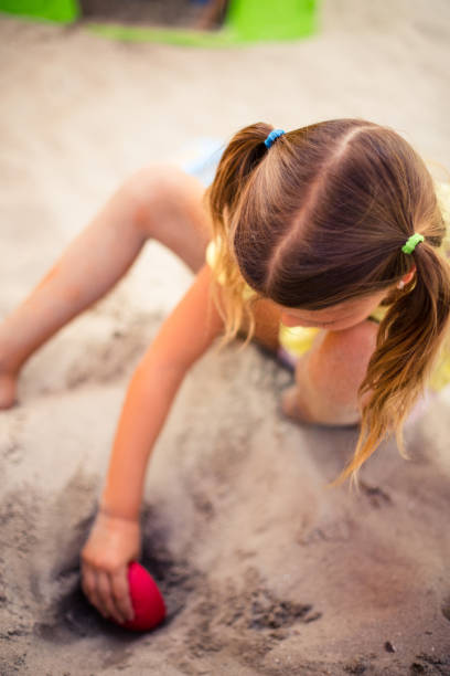 I am created little girl. School girl playing i sand and making shape. Space for copy. Close up.
