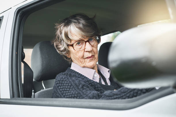 istock Senior woman driver smiles at camera through car window 1034239174