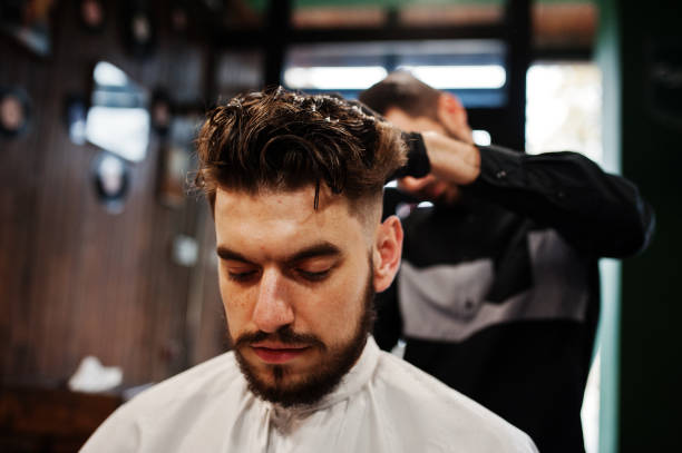 istock Handsome bearded man at the barbershop, barber at work. 1034244878