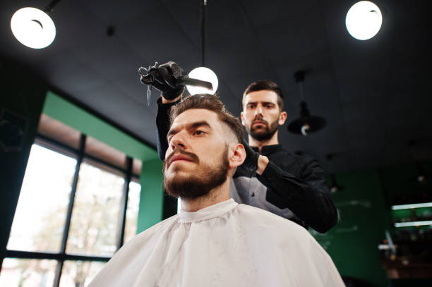 istock Handsome bearded man at the barbershop, barber at work. 1034245172