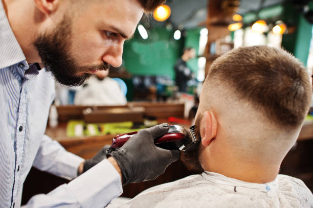 istock Handsome bearded man at the barbershop, barber at work. 1034245260