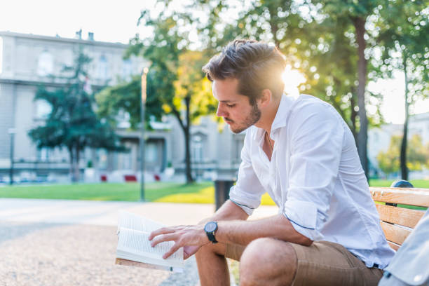 istock Young man reading book in park copy space 1034245918