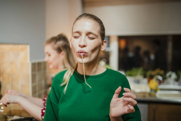 Spaghetti Fun at a Dinner Party Young woman is posing for the camera with spaghetti hanging out her mouth. indulgence stock pictures, royalty-free photos & images