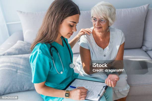 Nurse Measuring Blood Pressure Of Senior Woman At Home Stock Photo - Download Image Now