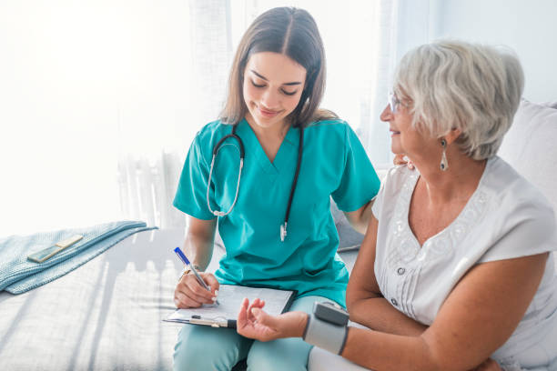 Older person is having blood pressure checked Nurse measuring blood pressure of senior woman at home. Smiling to each other. Young nurse measuring blood pressure of elderly woman at home. Doctor checking elderly woman's blood pressure home caregiver stock pictures, royalty-free photos & images