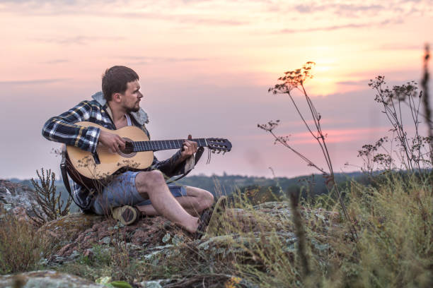 istock Guy with guitar play songs at sunny nature 1034257390