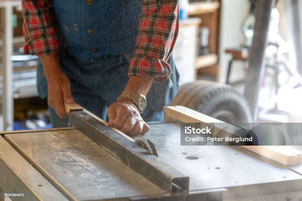 Man sawing a piece of wood A man is using an electric sawing machine to saw a piece of wood. The photo is a close-up of his hands and the machine. Active Seniors Stock Photo