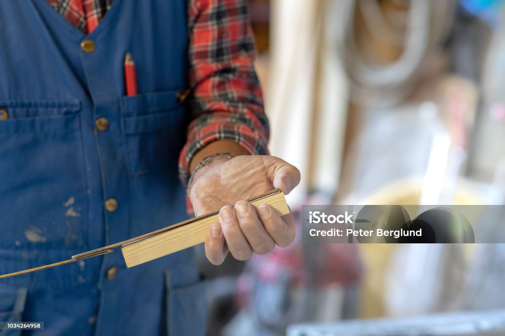 Man measuring a piece of wood A man is measuring a piece of wood. He's wearing a flannel shirt and a safety suit. The photo is a close-up of his hand. Adult Stock Photo