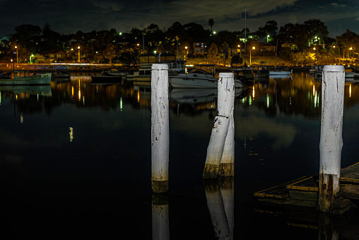 Sydney, Australia - Jun 14, 2014: Old submerged wooden jetty in Parramatta River at Lilyfield. Moored boats around the area. Image taken at dusk.